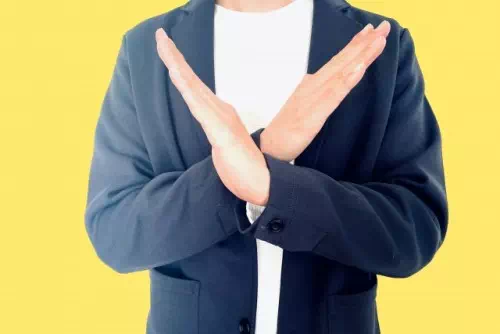 両腕でバツ印を作る男性